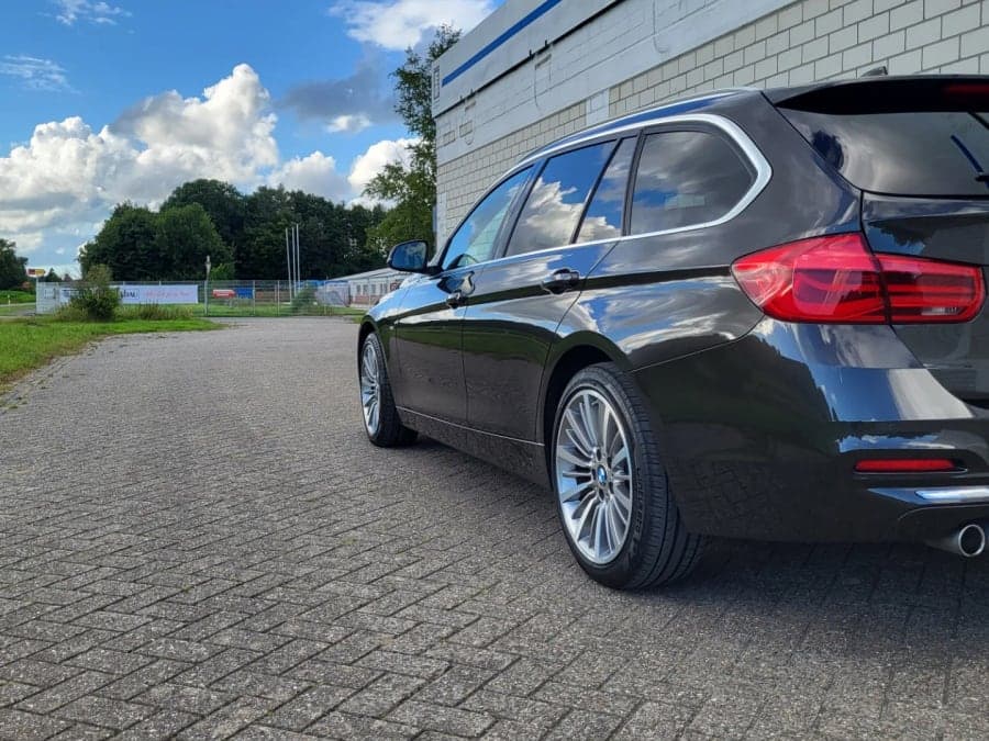 Schwarzer BMW Kombi von schräg hinten auf gepflastertem Hof