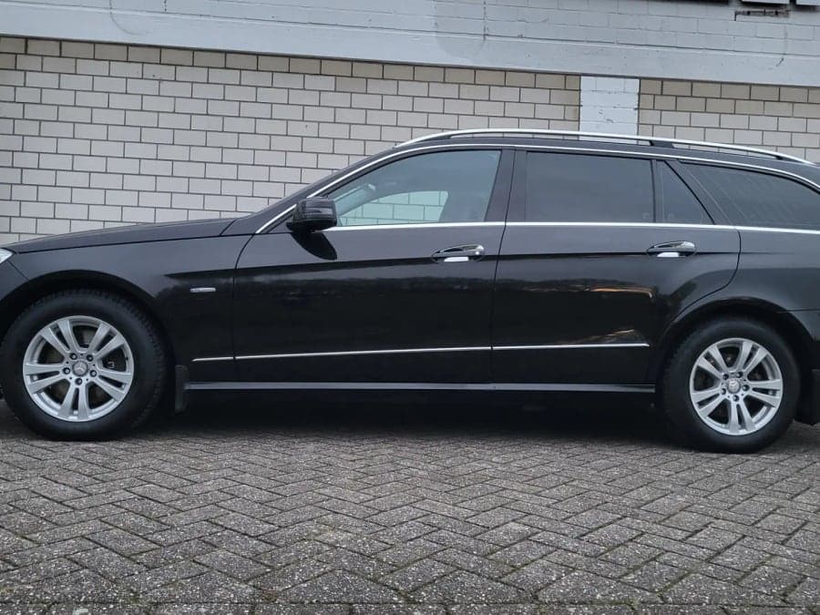Schwarzer Mercedes Kombi im Seitenprofil vor einer Halle