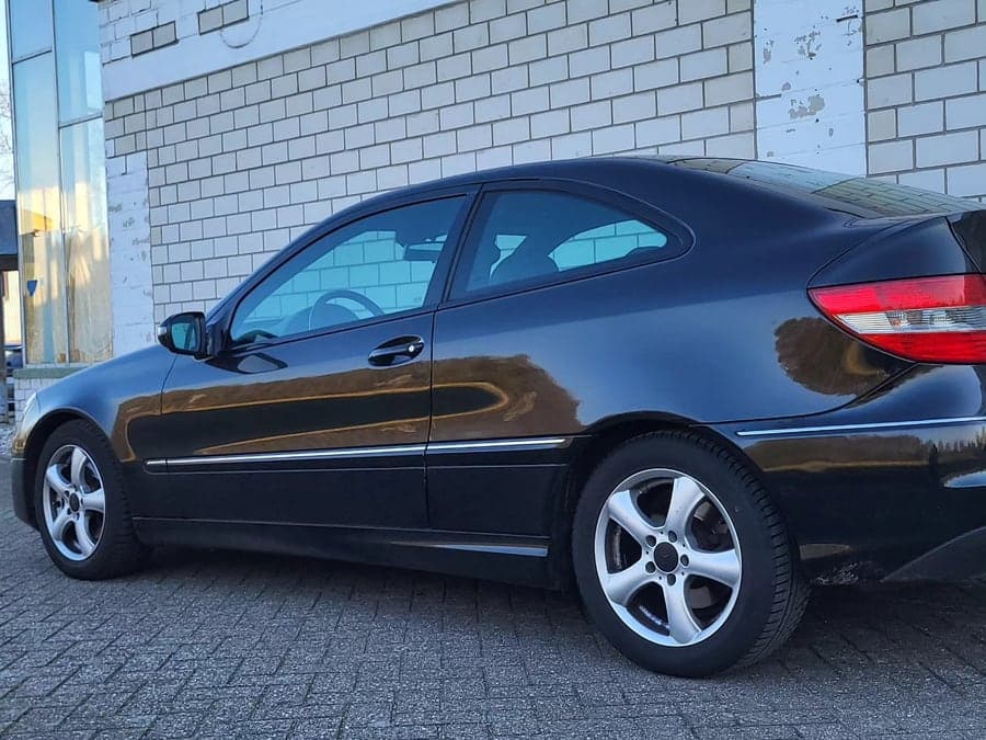 Schwarzes Mercedes Coupé von der Seite und von hinten
