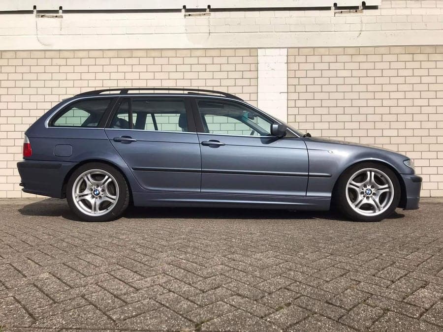 Blaugrauer BMW Kombi im Seitenprofil vor einer Halle